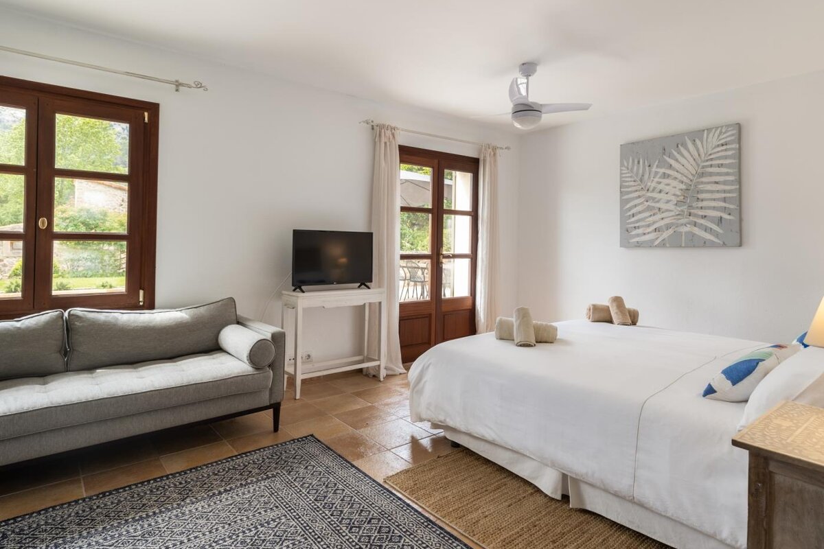 A bedroom with a bed a couch and a television