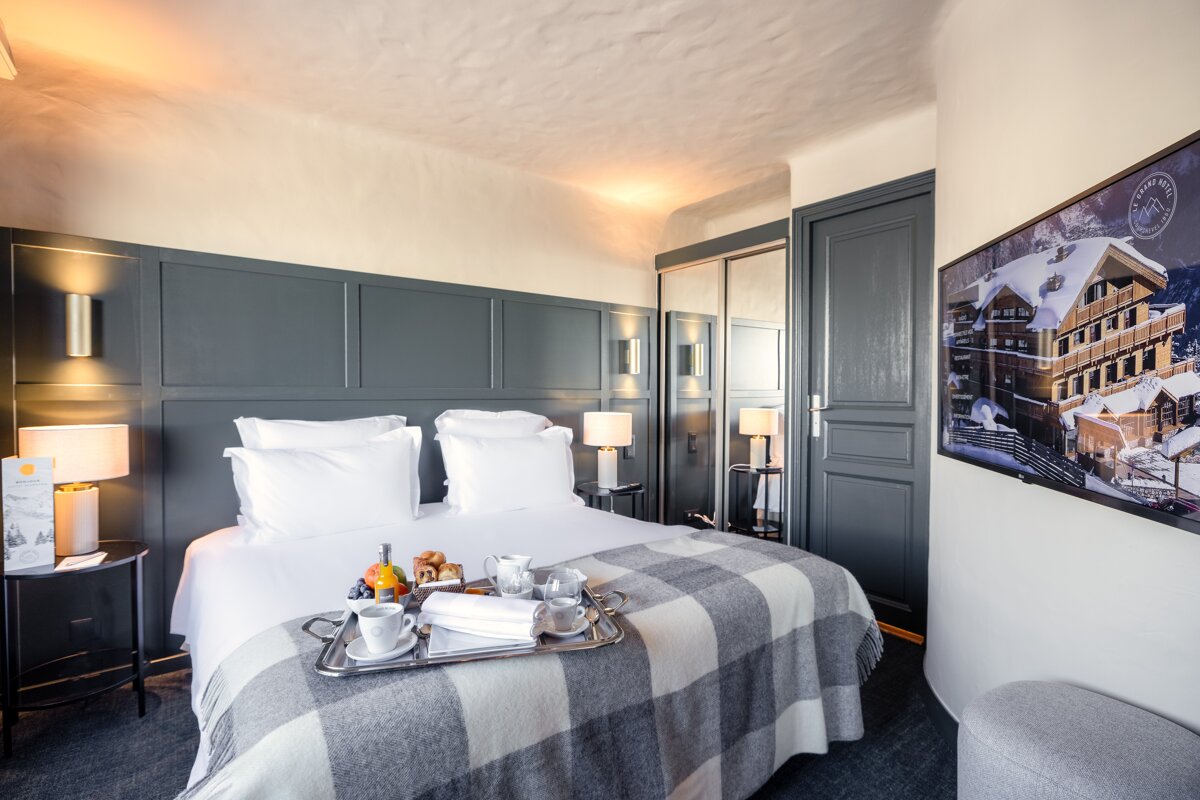 A hotel room with a tray of food on the bed