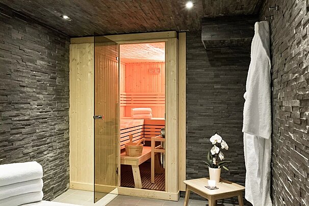 A sauna with a glass door and a white robe