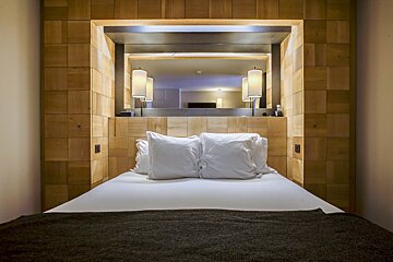 A bed with white pillows and a mirror behind it