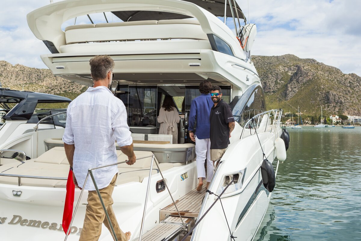 A man walking towards a boat that says ' s demeano ' on the back