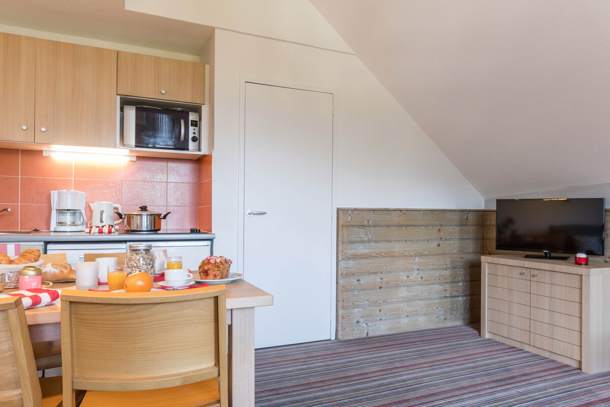A kitchen with a table and chairs and a television