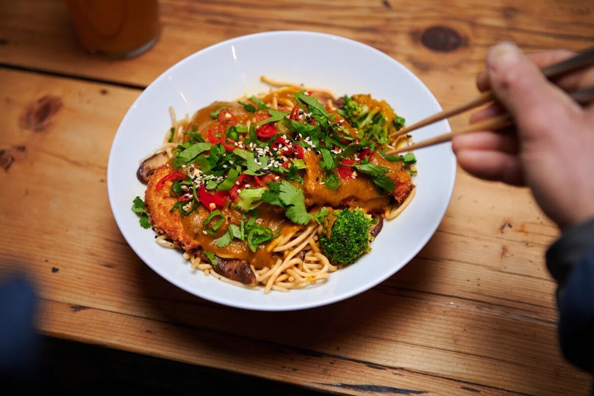 A person is eating a bowl of food with chopsticks