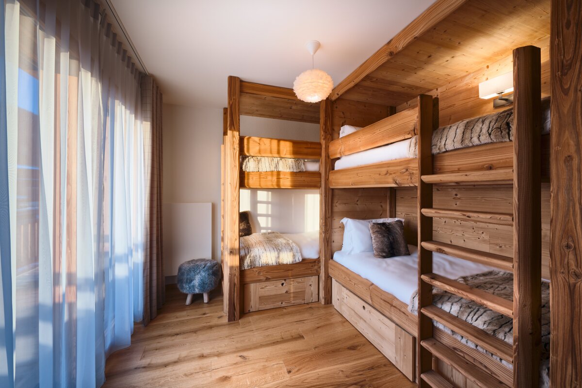 A bedroom with three bunk beds made of wood