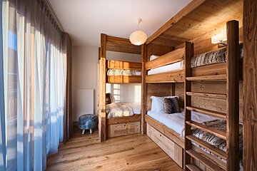 A bedroom with three bunk beds made of wood