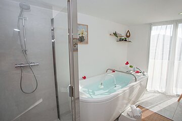 A bathtub in a bathroom next to a shower