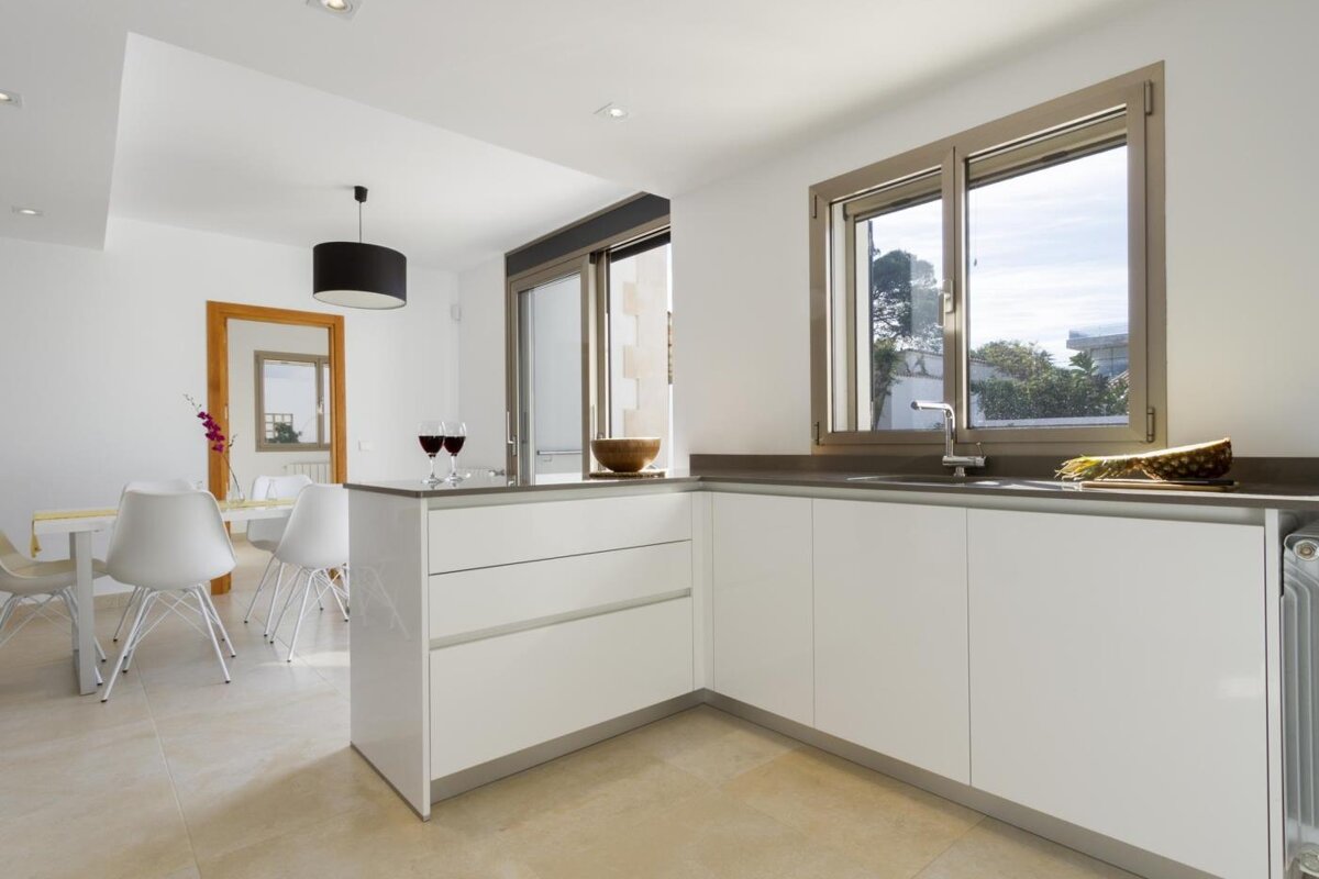 A kitchen with white cabinets and two glasses of wine on the counter