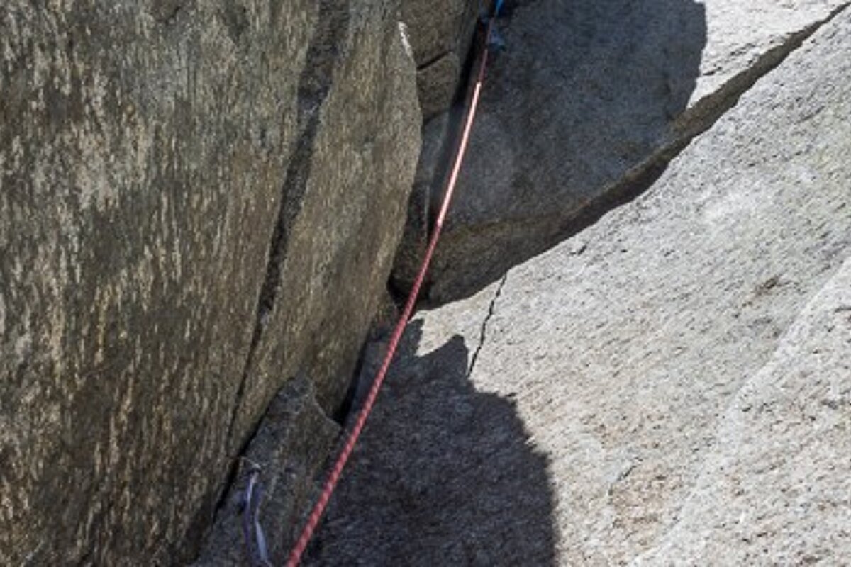 A person is climbing a rock wall with a rope attached to it