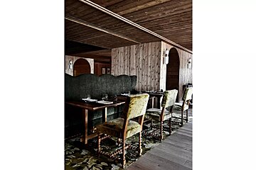 A dining room with tables and chairs and a wooden ceiling