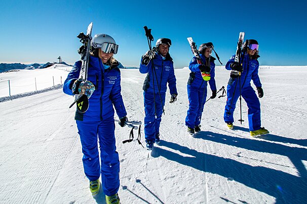 A group of skiers are walking down a snow covered slope