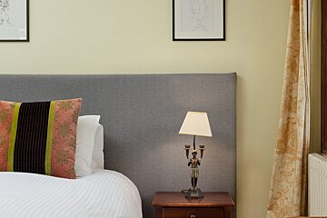 A lamp sits on a nightstand next to a bed