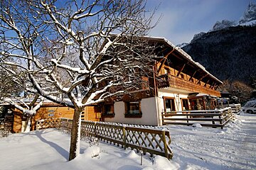 A snowy house with a fence in front of it