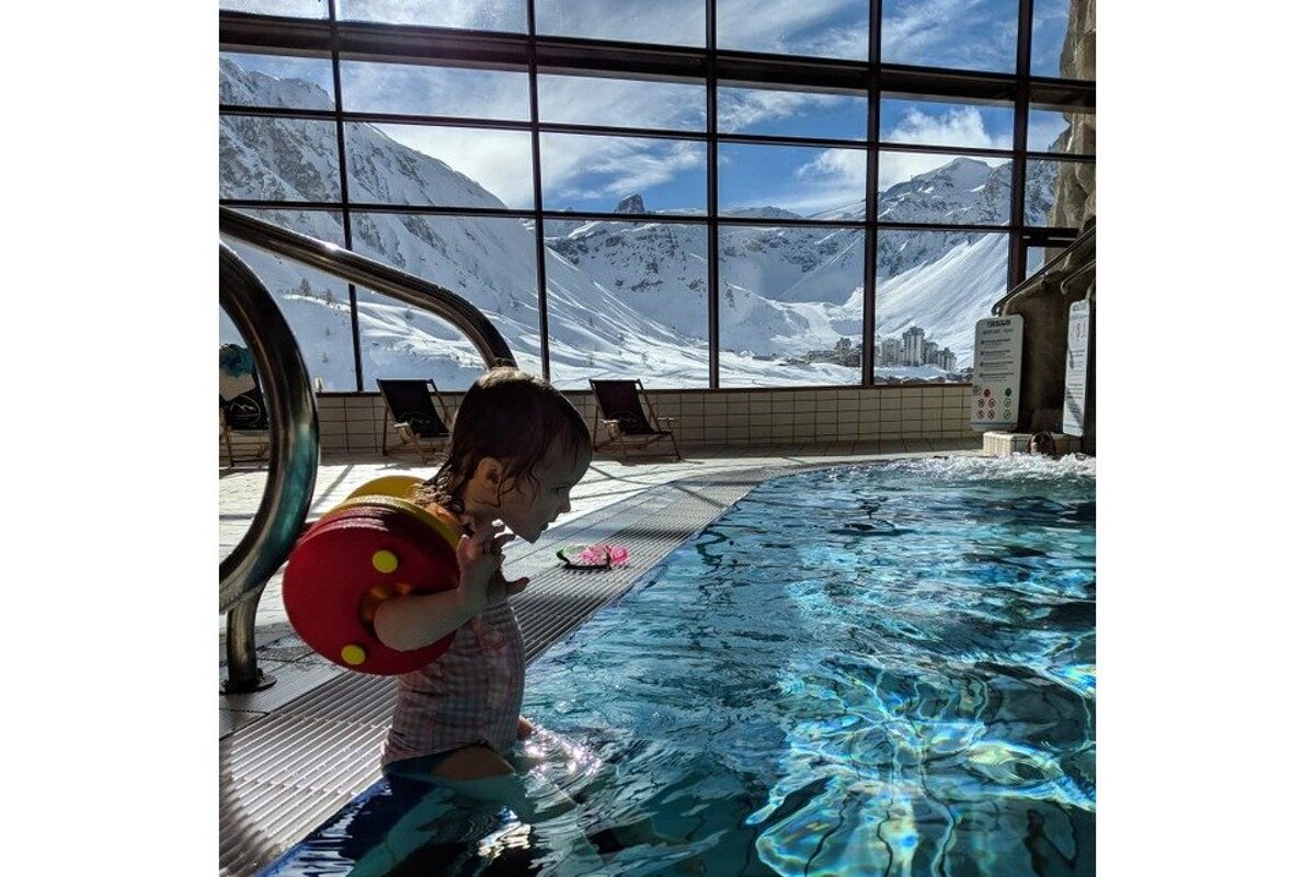 A little girl in a swimming pool with mountains in the background