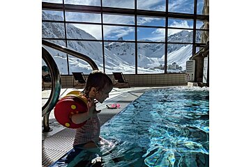 A little girl in a swimming pool with mountains in the background