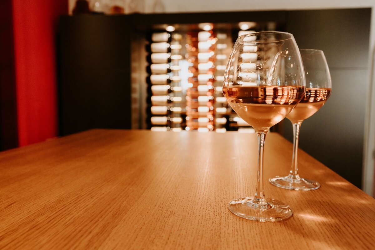 Two glasses of wine sit on a wooden table