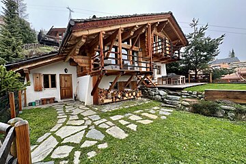 A large wooden house with a stone walkway leading to it