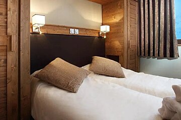 A hotel room with a bed and two pillows
