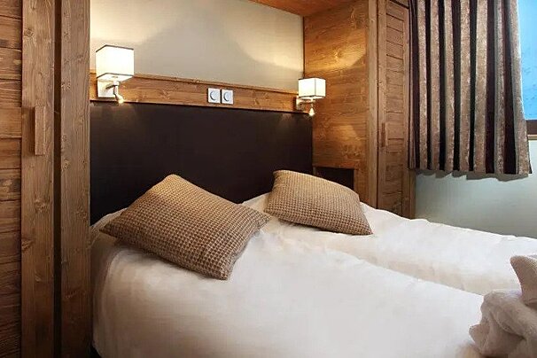 A bedroom with a bed , two pillows , a window and wooden walls