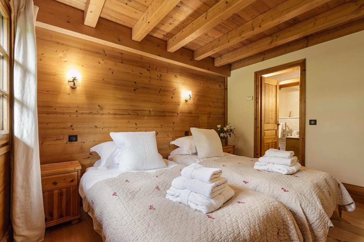 A bedroom with two beds and a wooden ceiling