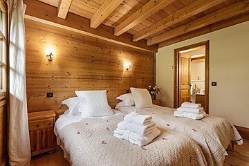 A bedroom with two beds and a wooden ceiling