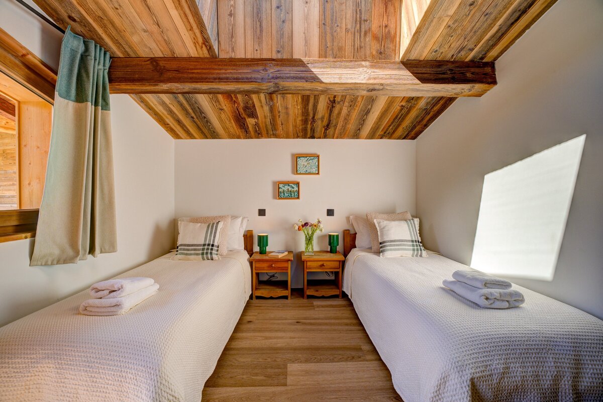 A bedroom with two twin beds and a wooden ceiling