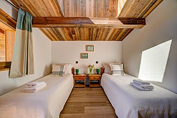 A bedroom with two twin beds and a wooden ceiling