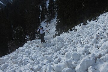 lumpy avalanche debris with a ski tourer crossing over