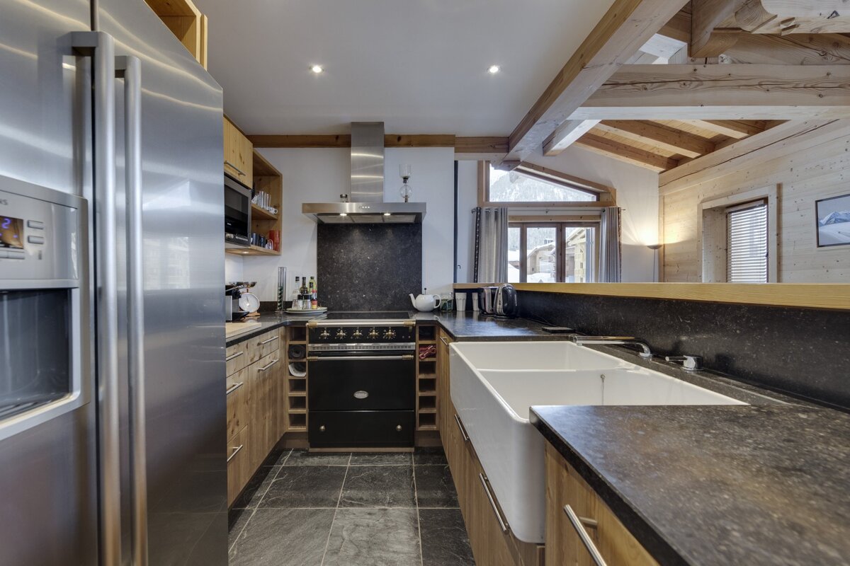 A kitchen with a stainless steel refrigerator and a black stove