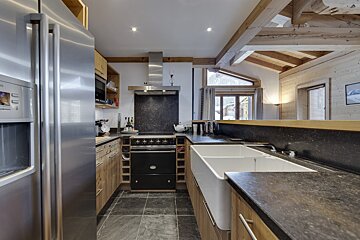 A kitchen with a stainless steel refrigerator and a black stove