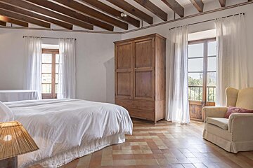 A bedroom with a bed a chair and a wardrobe