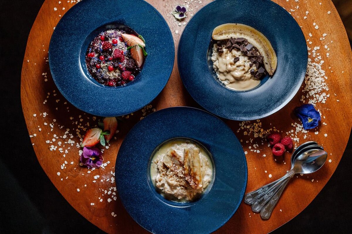 Three blue bowls of food are on a wooden table