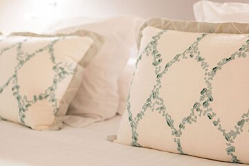 A white pillow with a green pattern on it sits on a bed