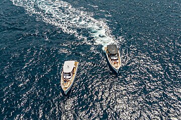 Two boats are floating in the ocean and one of them has the word yacht on the side