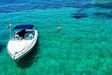 A woman is swimming in the ocean next to a boat