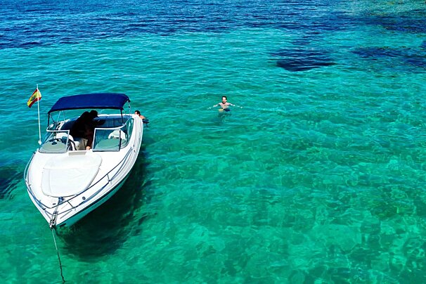 A woman is swimming in the ocean next to a boat