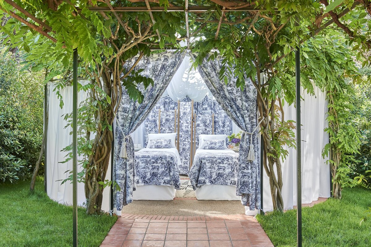 Two beds under a canopy with blue and white curtains