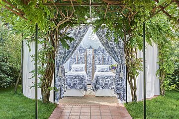 Two beds under a canopy with blue and white curtains