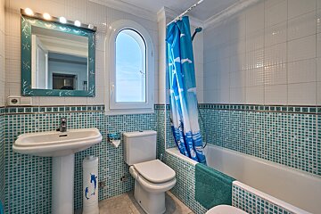 A bathroom with a blue shower curtain with dolphins on it