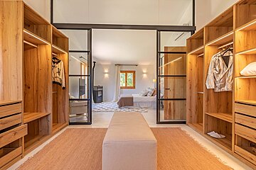 A walk in closet with a sliding glass door leading to a bedroom
