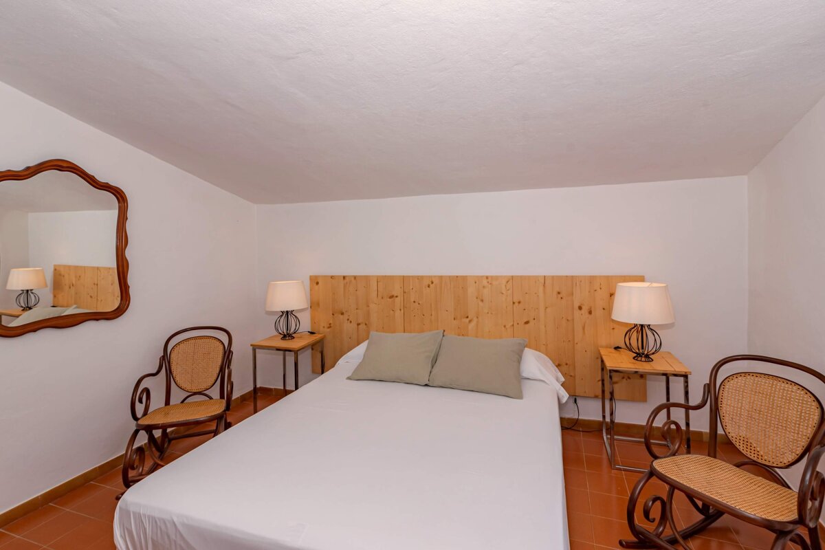 A bedroom with a bed and two rocking chairs