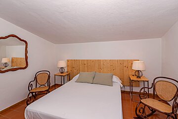 A bedroom with a bed and two rocking chairs