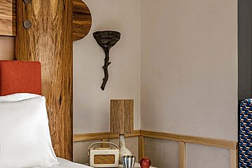 A bedroom with a wooden headboard and a lamp on the nightstand
