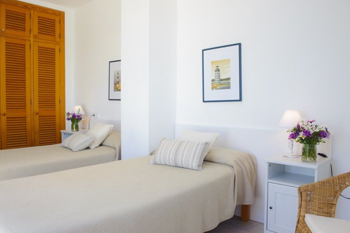 A bedroom with two beds and a picture of a lighthouse on the wall