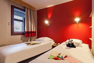 A bedroom with two beds and a stuffed panda on the bed