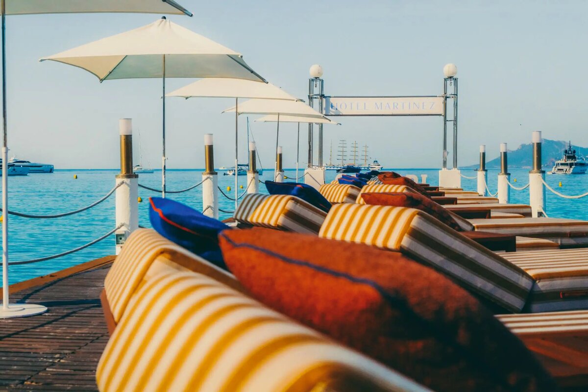 A row of lounge chairs on a dock with a sign that says hotel martinez
