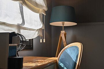 A lamp with a blue shade sits on a desk next to a chair