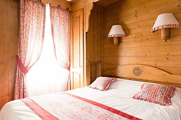 A bedroom with a bed and two lamps on the wall