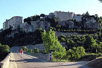 A woman is walking across a bridge with a castle in the background
