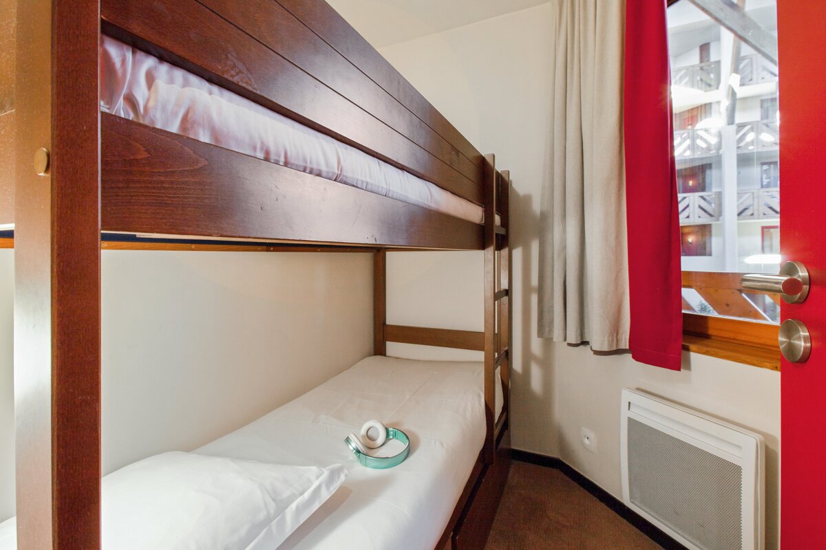 A bunk bed in a room with a red door