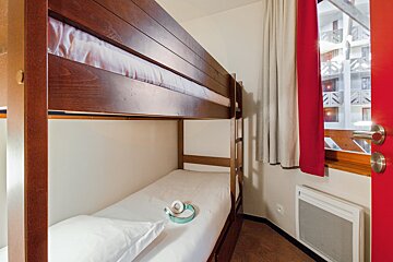 A bunk bed in a room with a red door
